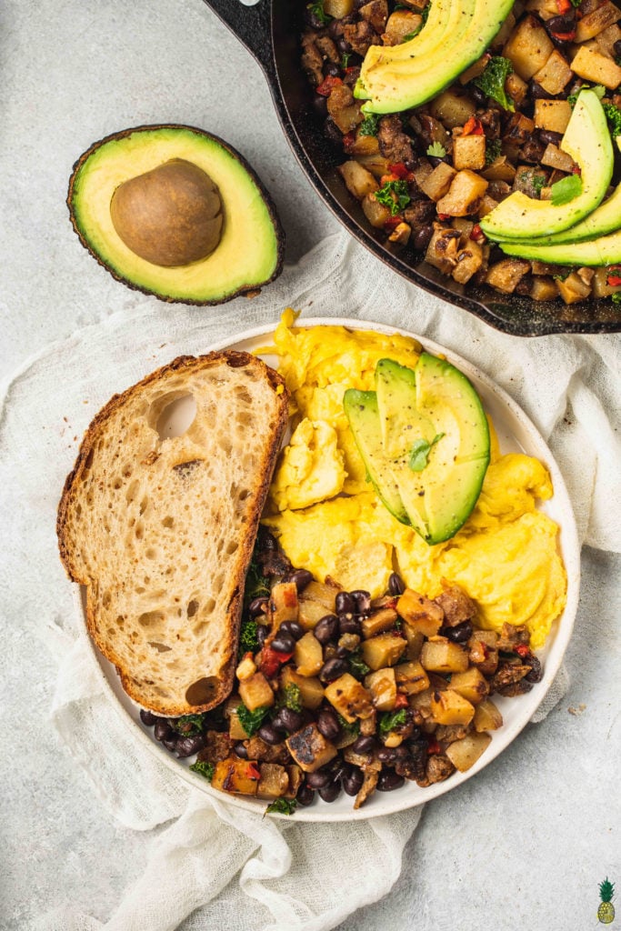 Vegan breakfast plate with vegan eggs, breakfast hash, toast and avocado
