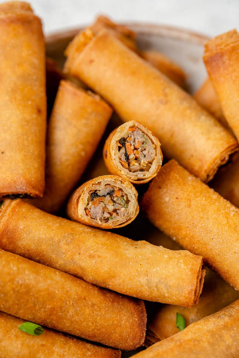 macro image of lumpiang shanghai cut in half in bowl surrounded by more by sweet simple vegan