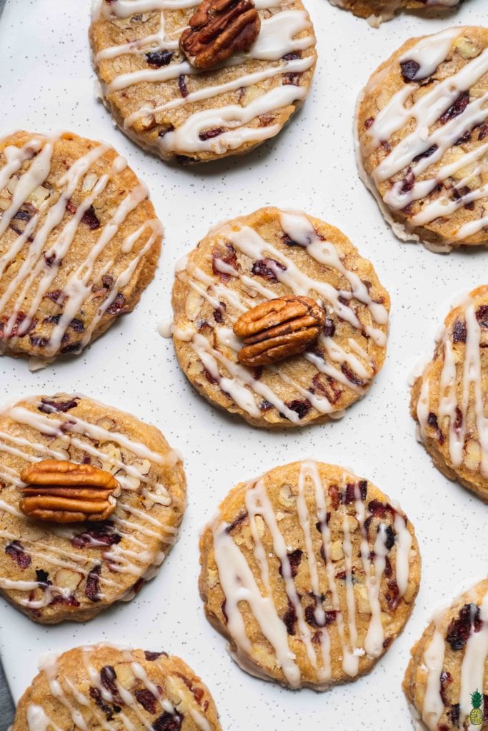 Christmas Recipe - Overhead shot of pecan cranberry orange shortbread cookies with pecan garnishes on top on a white plate