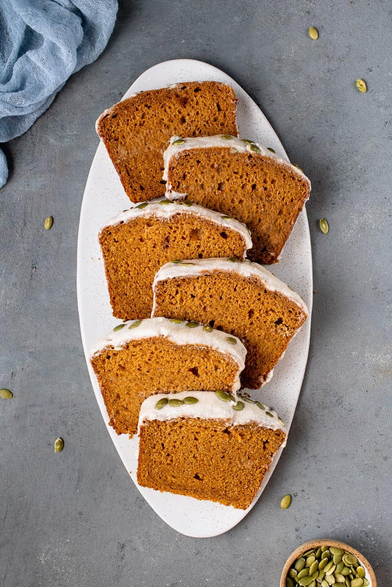 overhead photo of stacked slices of vegan pumpkin bread on white board