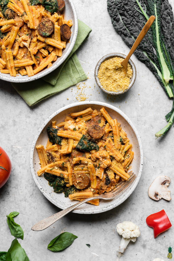 Gluten free pasta with roasted red pepper and tomato sauce in a ceramic bowl; food photograph by sweet simple vegan