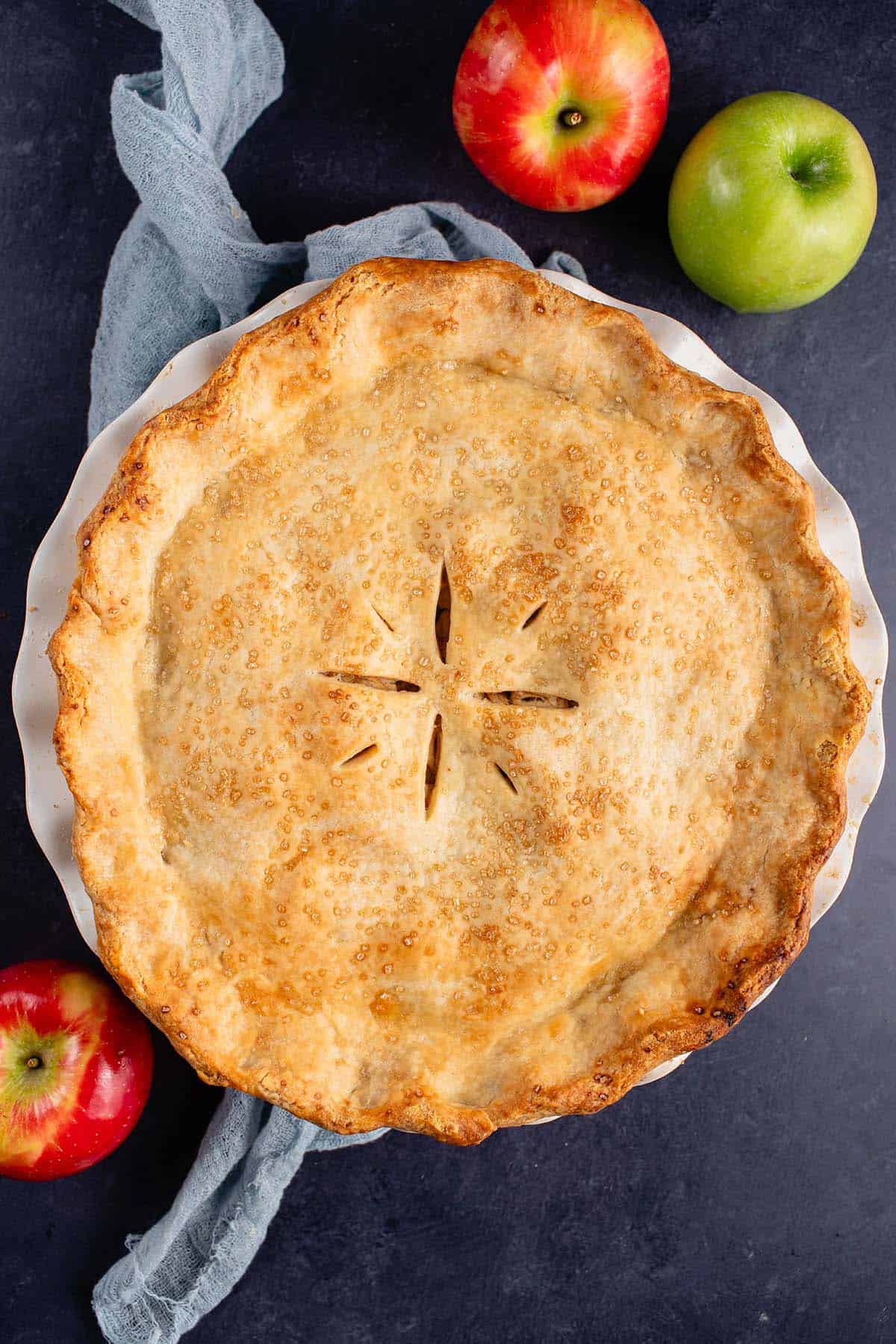 Overhead photo of vegan apple pie on blue backdrop
