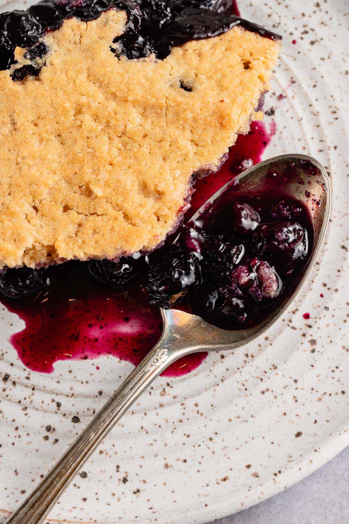 close up of slice of blueberry cobbler on white plate