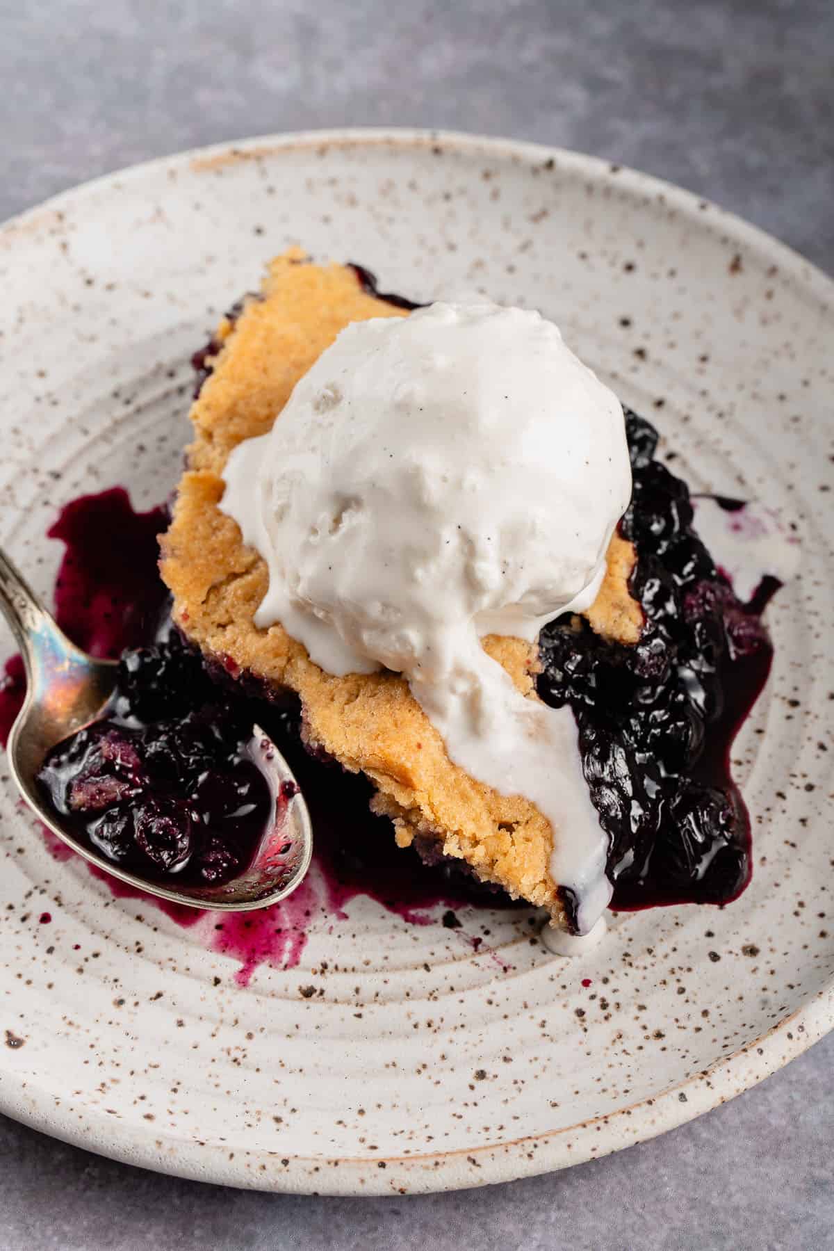 slice of blueberry cobbler with ice cream on white plate