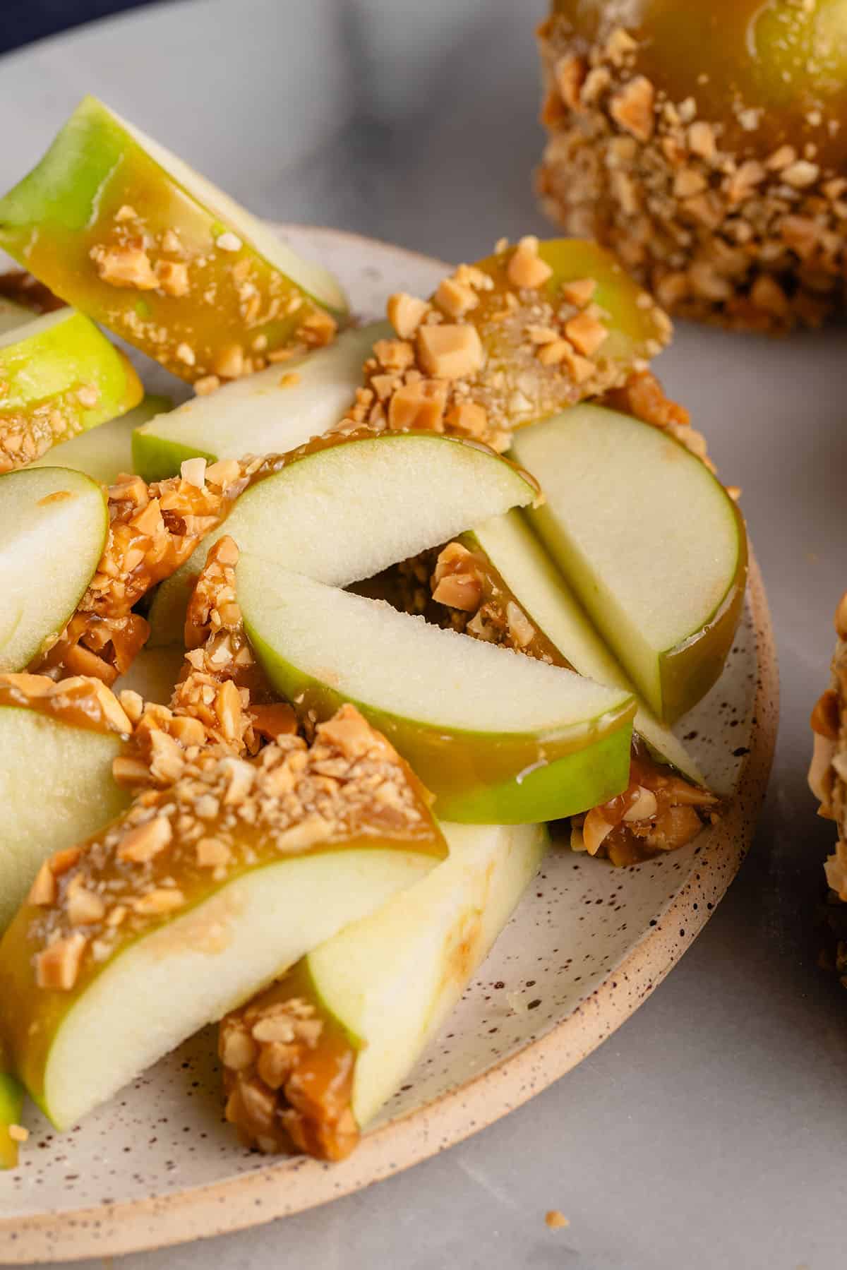 sliced caramel apple with peanuts on white plate
