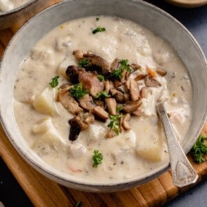 vegan clam chowder in gray bowl with spoon and parsley