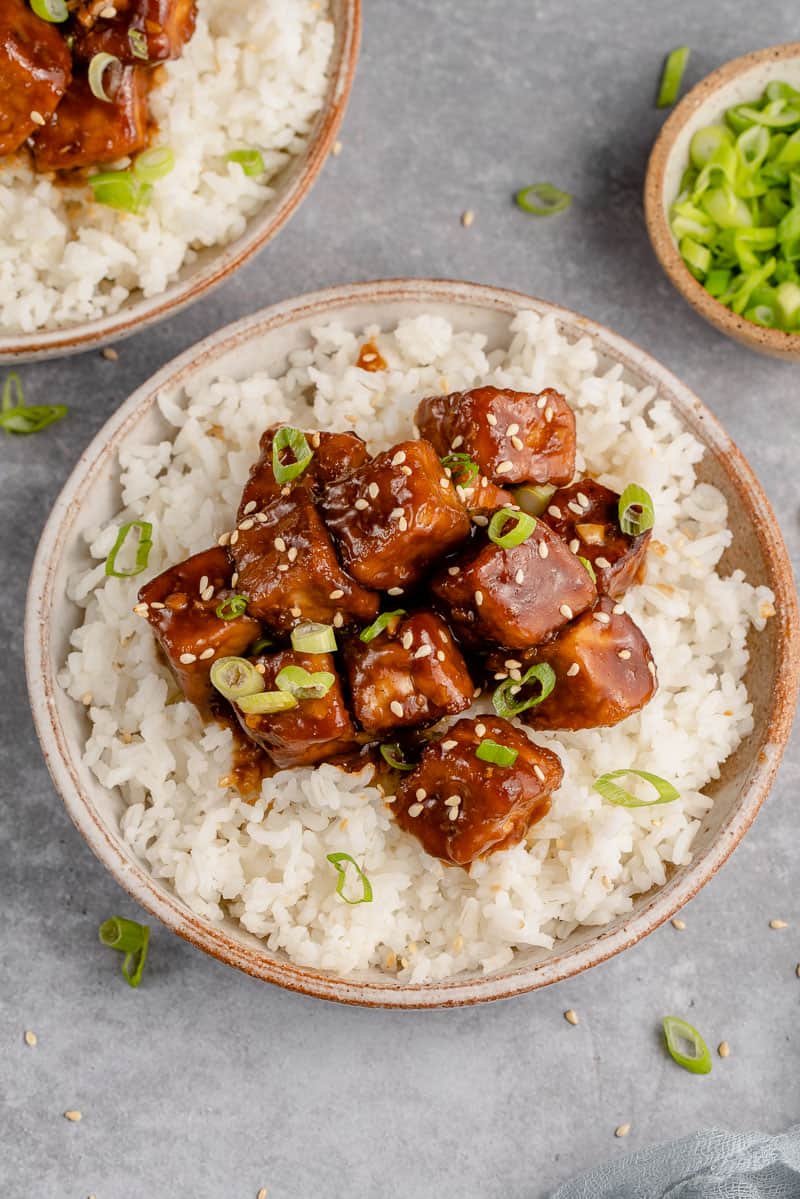 saucy vegan generalo tso's tofu in a bowl with rice