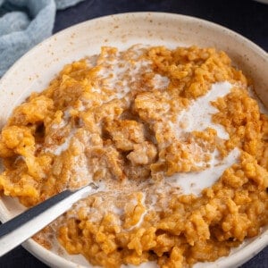 pumpkin rice pudding in a bowl with a spoon sticking out