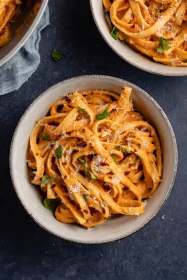 close up roasted red pepper sauce fettuccine in gray bowl